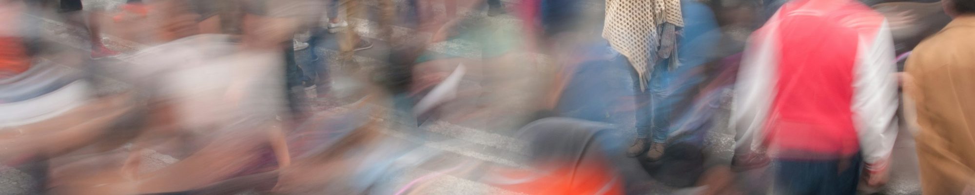Eine still stehende Person inmitten einer verwischten, hastenden Menschenmenge