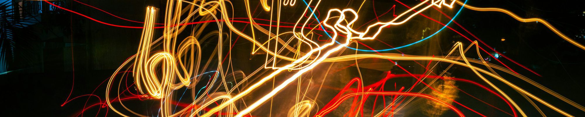 Rote und gelbe Lichtspuren einer Langzeitbelichtung auf schwarzem Grund