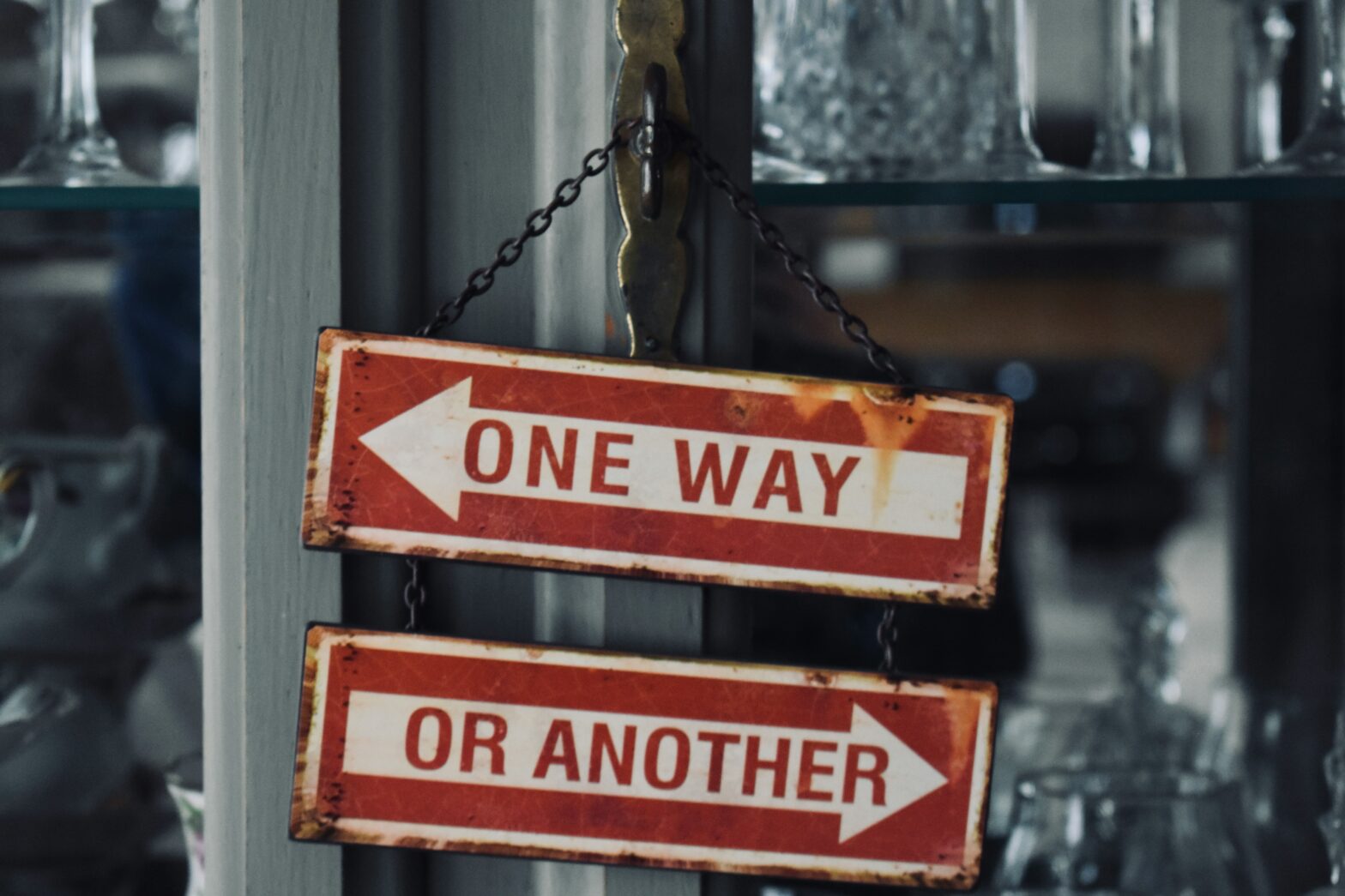 Zwei alte Wegweiserschilder mit gegenläufigen Pfeilen: One Way, Or Another